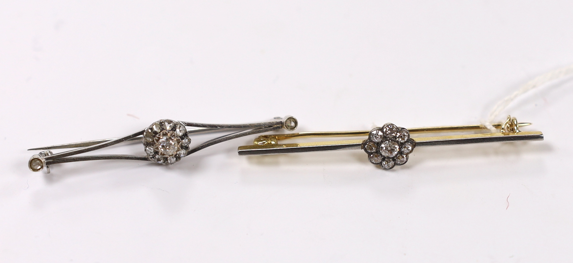 An early to mid 20th century, yellow metal and nine stone diamond cluster set flower head bar brooch, 56mm and one other similar white metal and diamond cluster set flower head bar brooch, with diamond set terminals, gro
